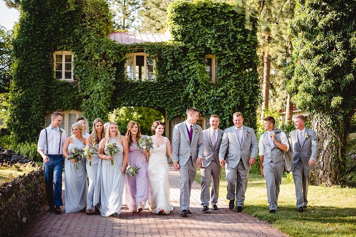 A photo of a wedding party in front of a lush overgrown gatehouse on the Estate grounds