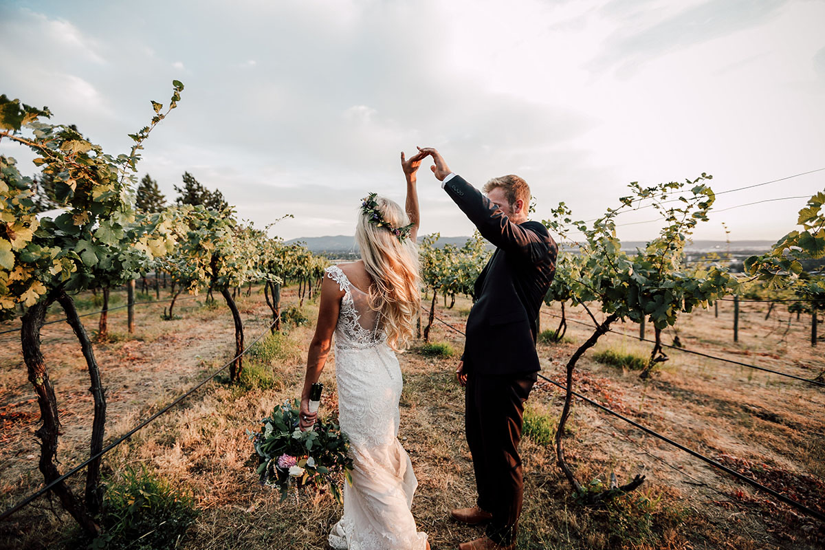 A photo of a bride and groom walking hand-in-hand through the vineyard