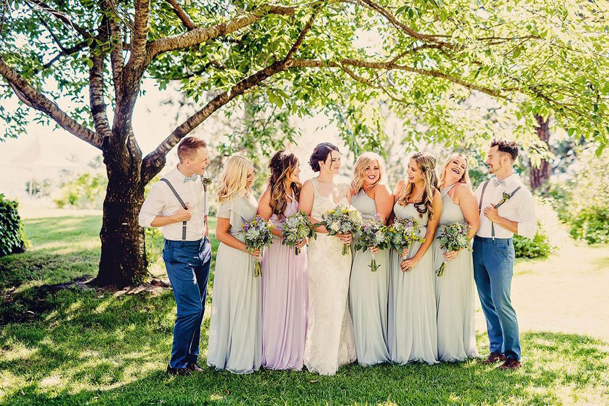 A photo of a wedding party beneath green trees