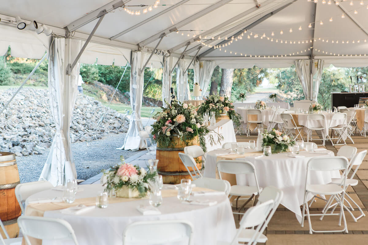 A photo of the interior of the wedding tent with flowers and set tables