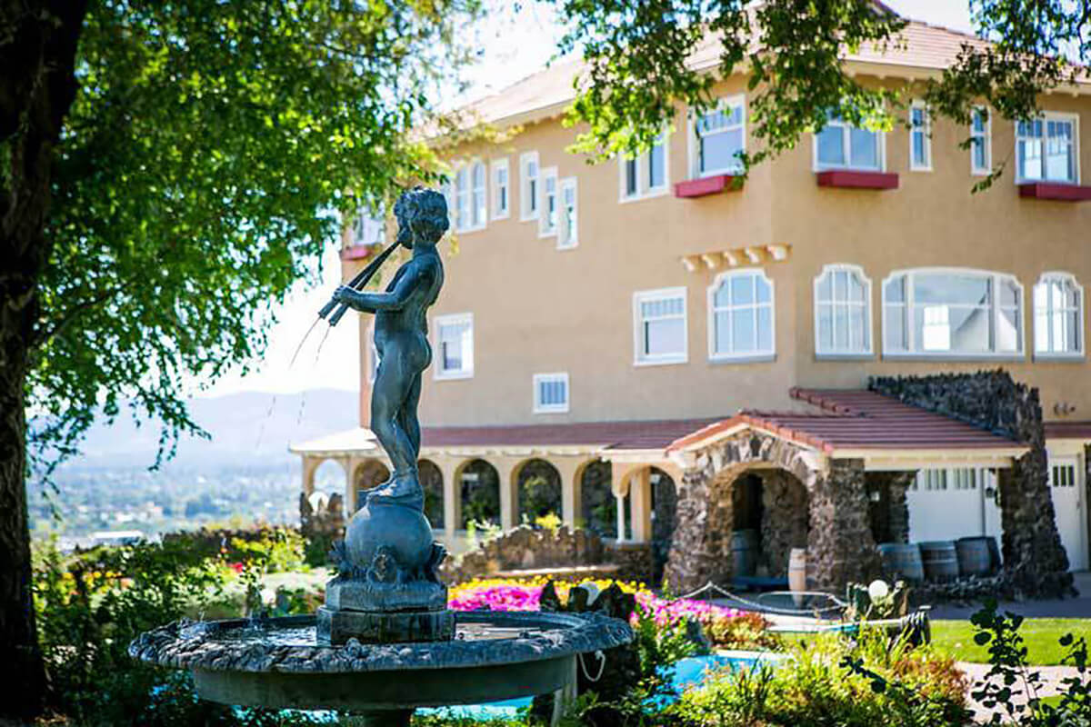 A sunlit photo of the Cliff House Estate with the sculptural fountain in the foreground and the Estate dominating the background.