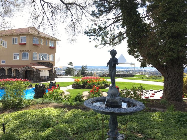 a photo of the Cliff House Estate grounds and garden with the Cliff House Estate in the left side of the frame a fountain in the center, and a tree on the right