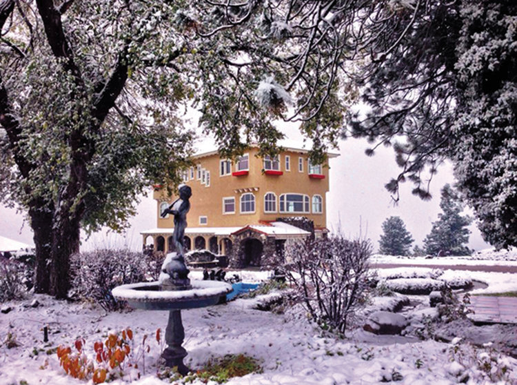 A winter-time photo of the Cliff House Estate grounds with the Cliff House Estate building framed centrally by snow-covered trees