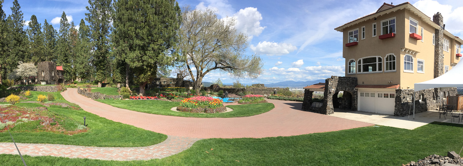 a panoramic view of the Cliff House Estate grounds with the Cliff House on the right hand side, the trail down the center of the frame, and trees on the left