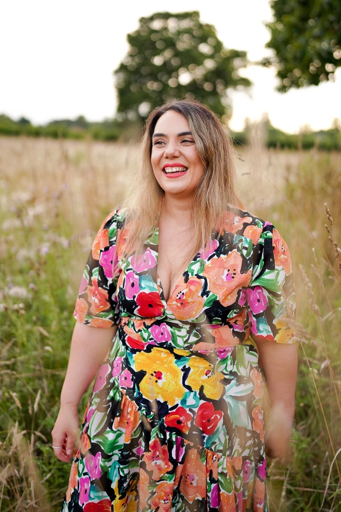 Woman in floral dress smiling in a field