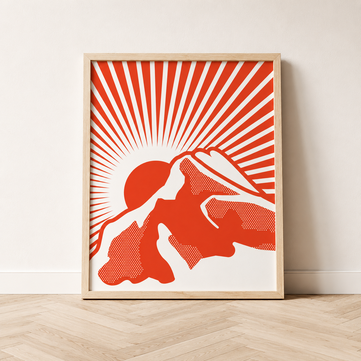 Framed Rundle Rising art print featuring a bright fire red illustration of Rundle Mountain with a rising sun and radiating lines on a cream background, displayed in a natural wood frame