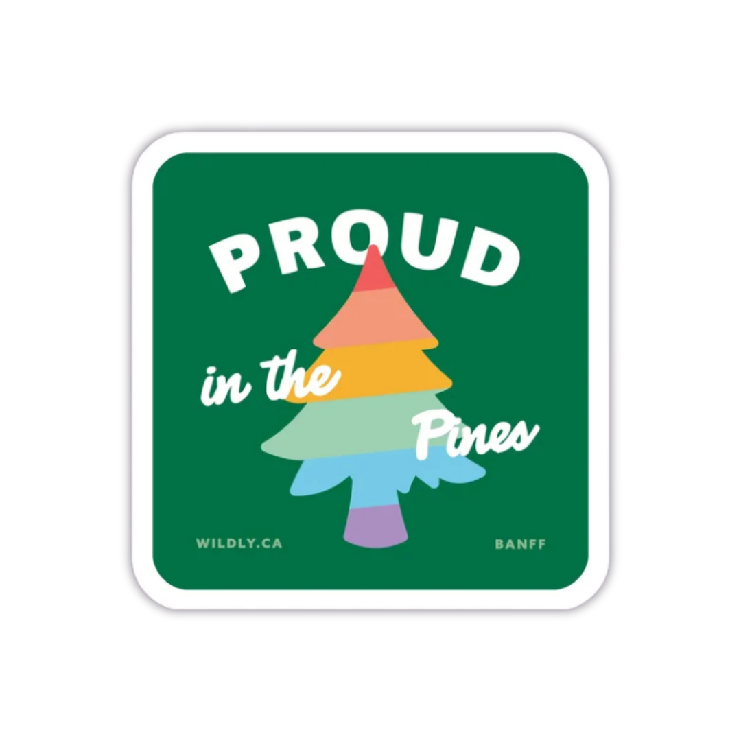 “Proud in the Pines” sticker with a rainbow-striped pine tree on a dark green background and a white border.
