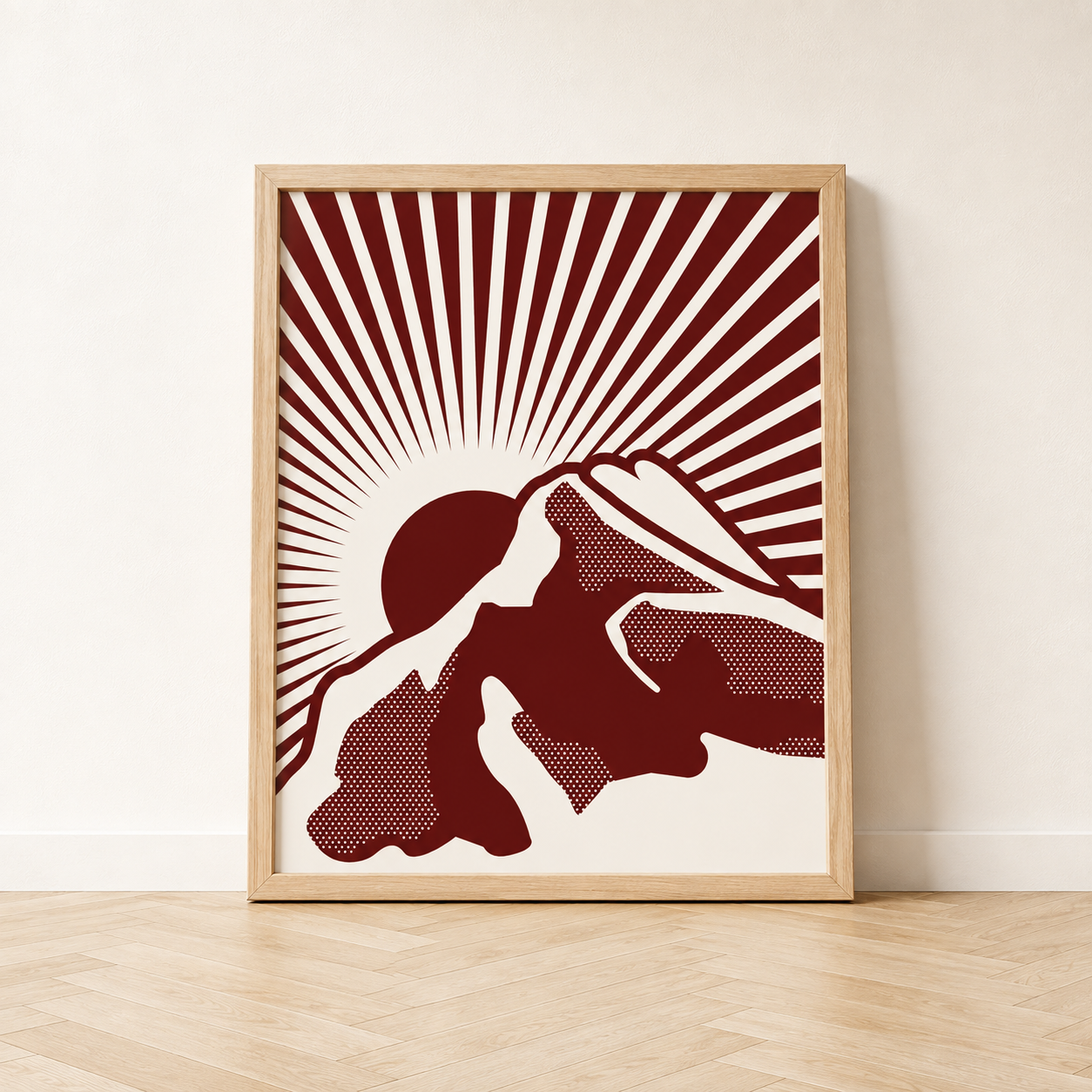 Framed Rundle Rising art print featuring a dark Ruby red illustration of Rundle Mountain with a rising sun and radiating lines on a cream background, displayed in a natural wood frame
