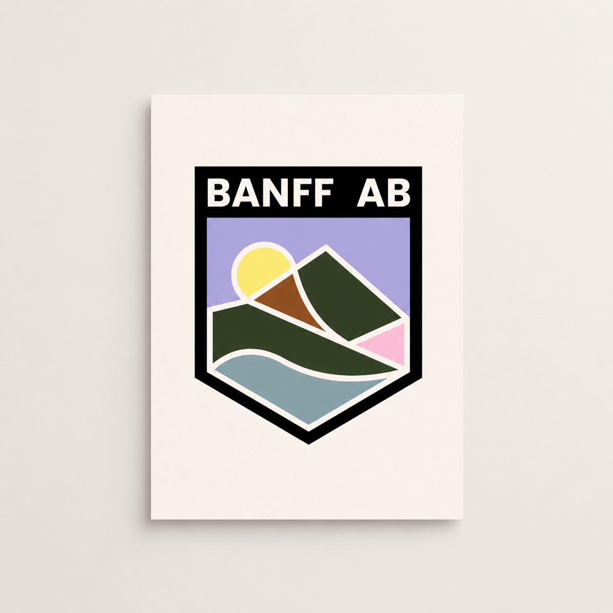 Banff Crest art print featuring bold “BANFF AB” lettering above a stylized mountain landscape with a yellow sun, dark green peaks, blue water, and pastel accents inside a black crest-shaped border.