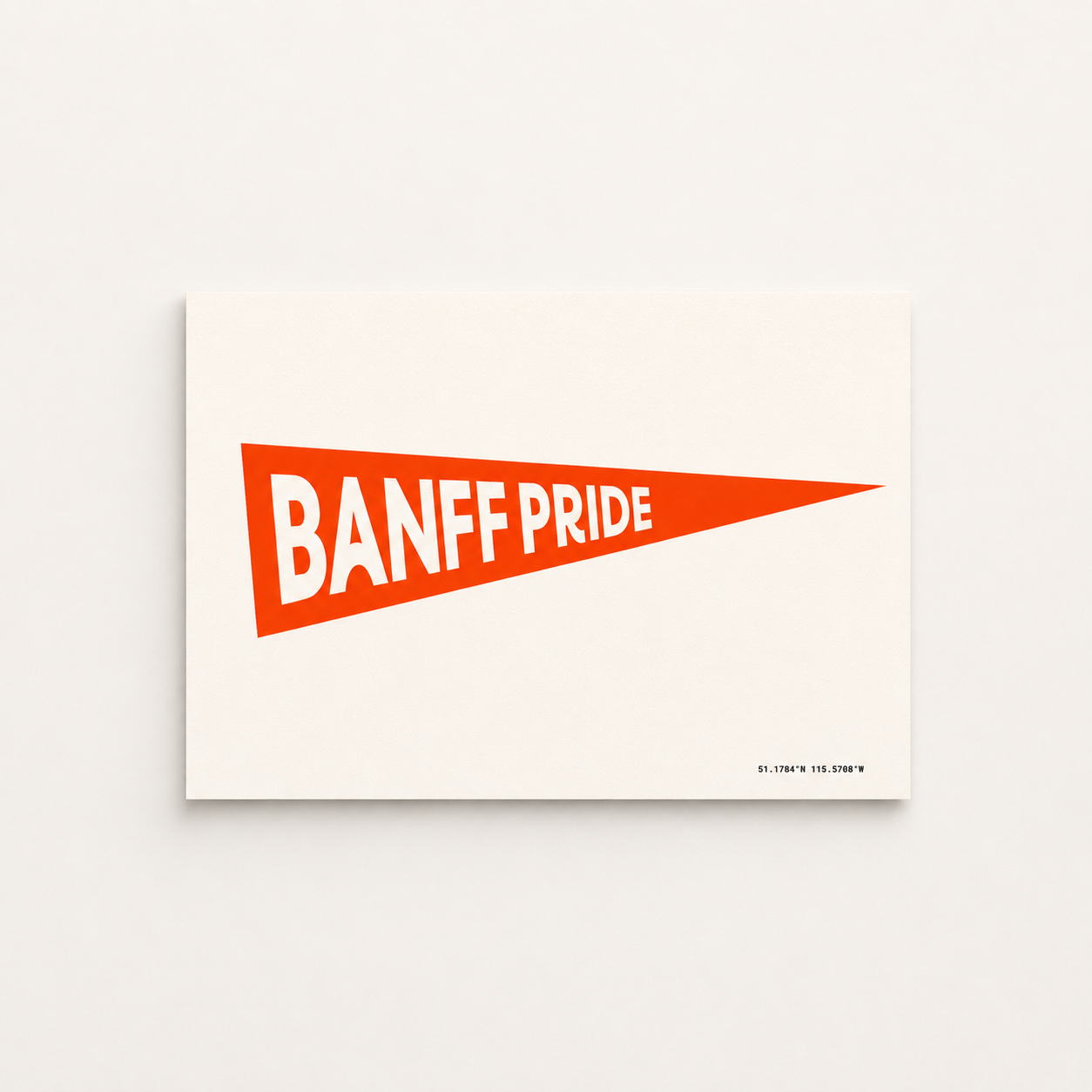 Banff Pride Pennant Flag art print featuring a bright fire red triangular pennant with bold white “Banff Pride” lettering and Banff coordinates on a cream background.