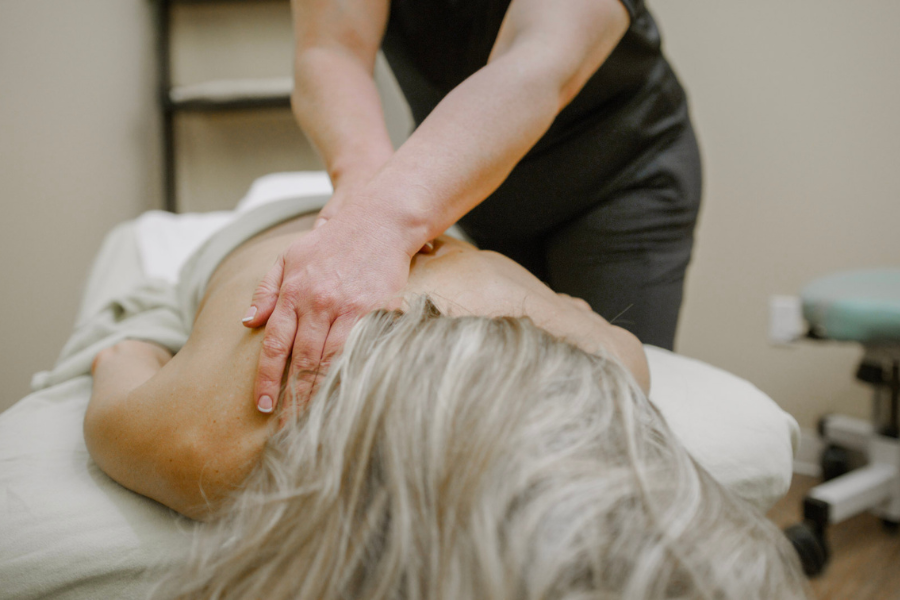 A massage therapist uses both hands to apply pressure to a client’s upper back and shoulders during a professional massage session at a wellness facility.