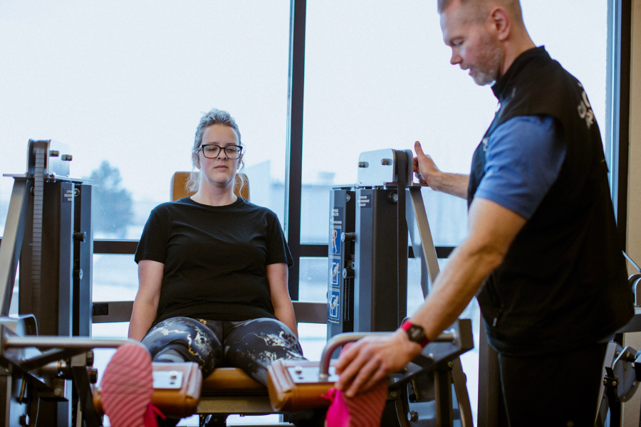 Personal training session at Club Apple health club in Idaho Falls with trainer guiding a member on strength equipment.