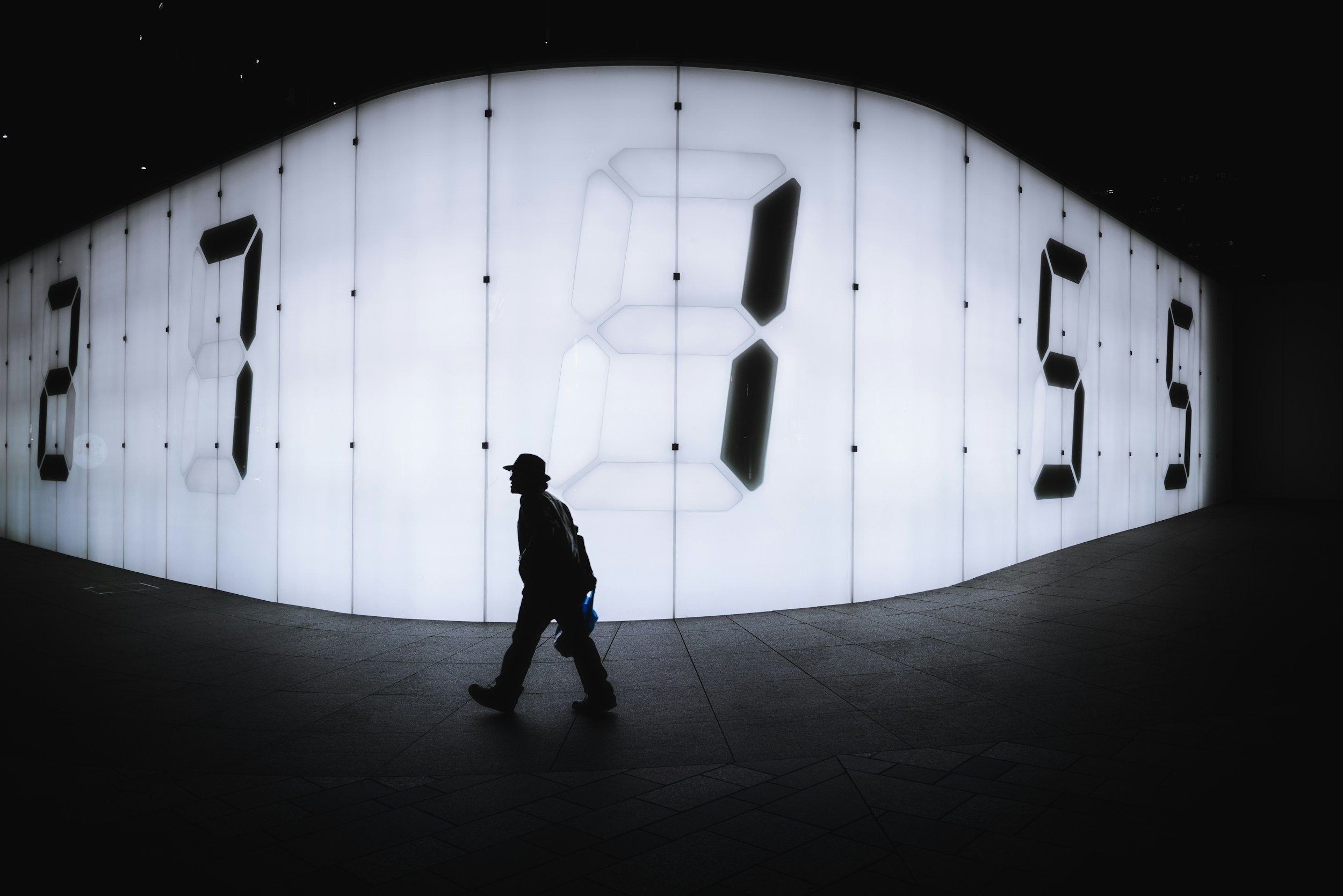 A man walking by a large wall of digital numbers.