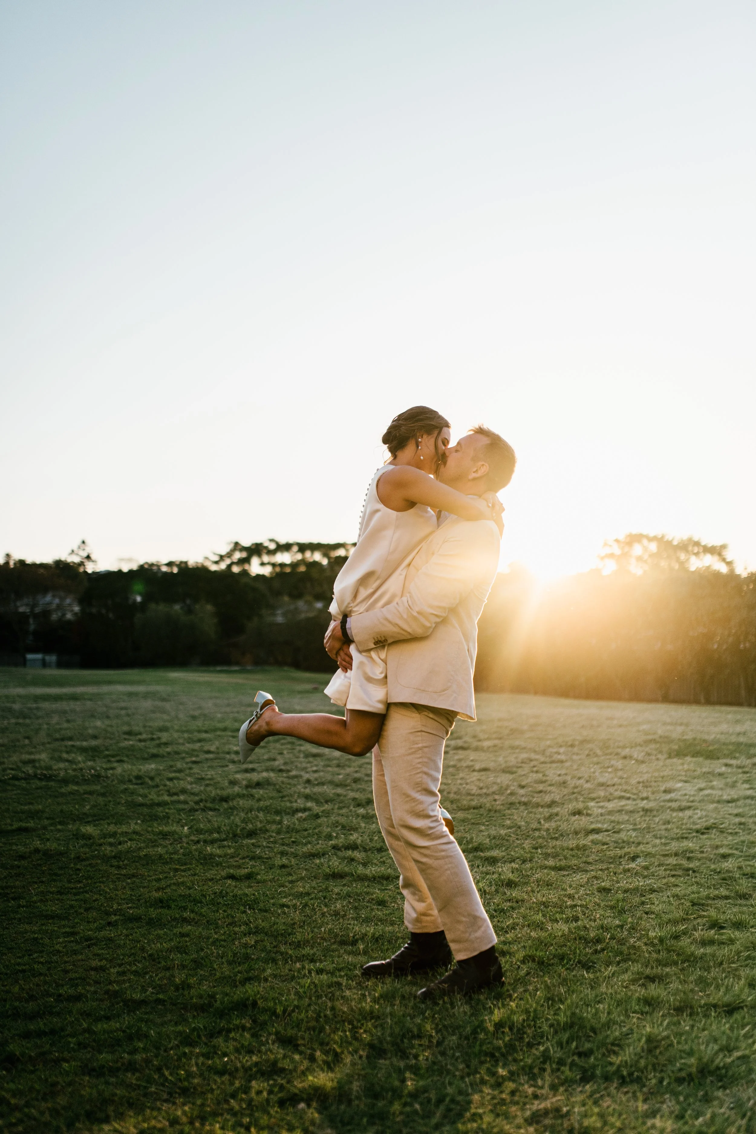 bride and groom kissing at sunset in new farm backyard wedding