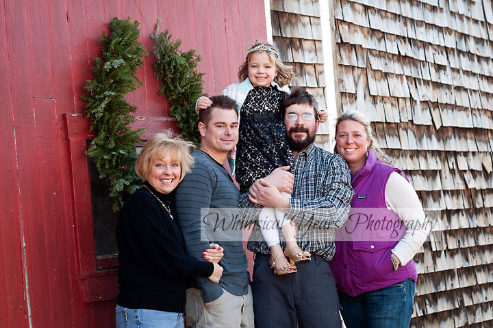 family portrait against a barn with red door at christmas time