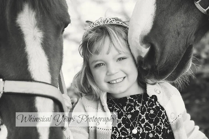 horse nuzzling the cheek of a little girl