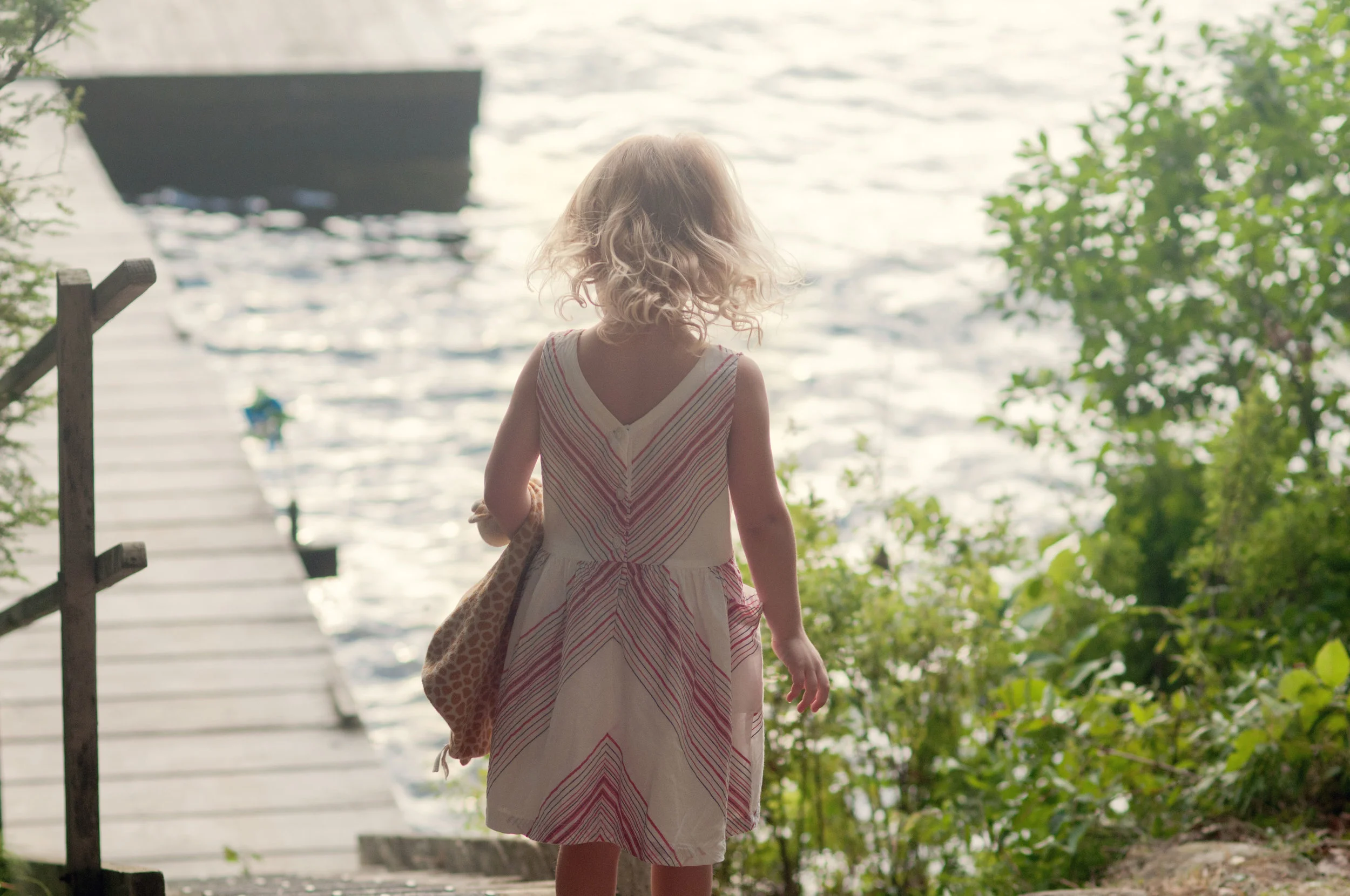 little girl walking to a dock at a lake