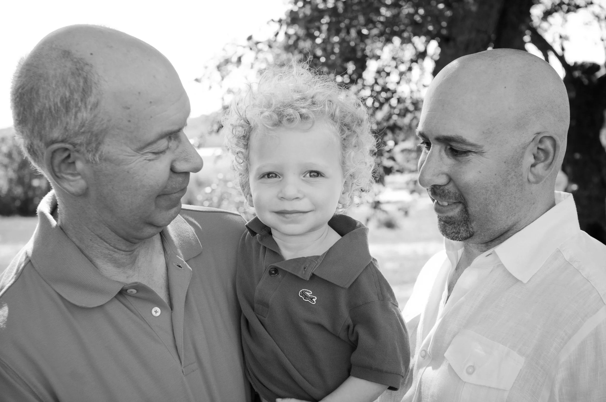 black and white photo of grandfather and adult son holding grandson