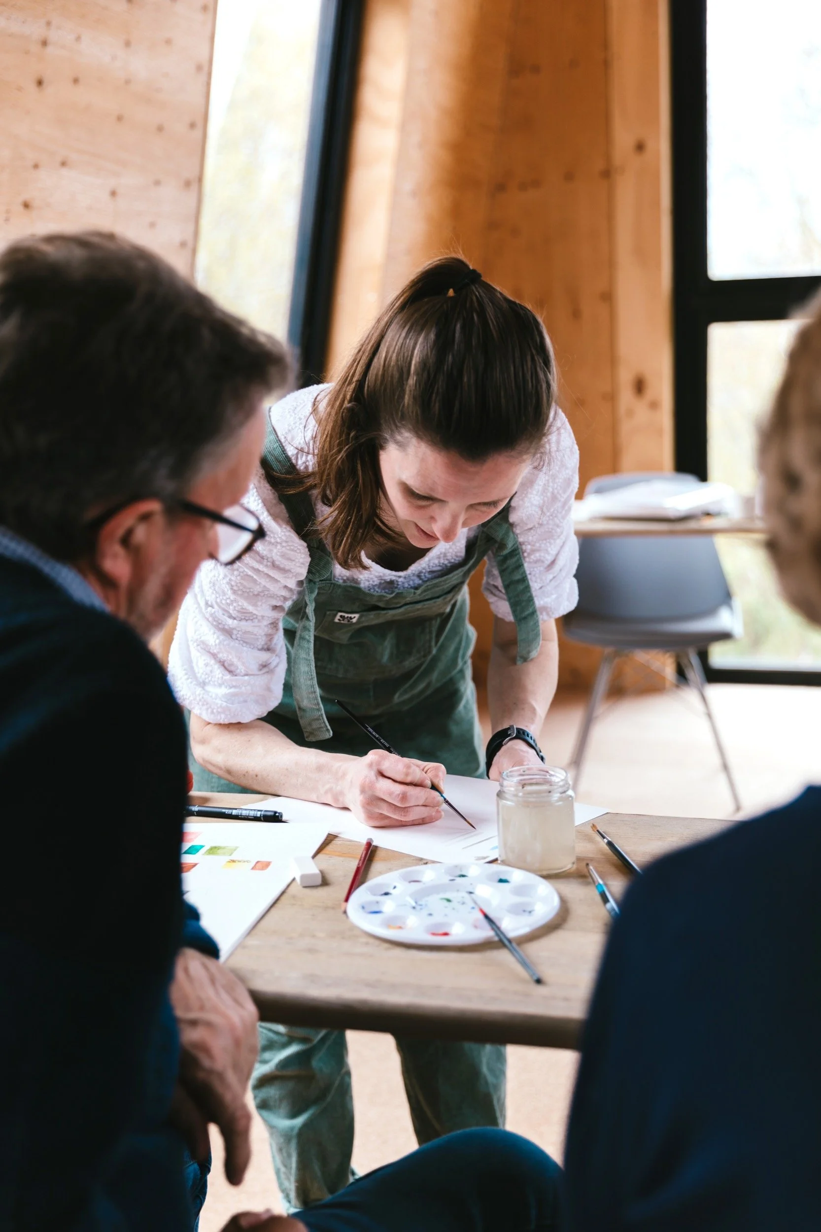 Watercolour artist Imogen Partridge helping an attendee at her watercolour workshop