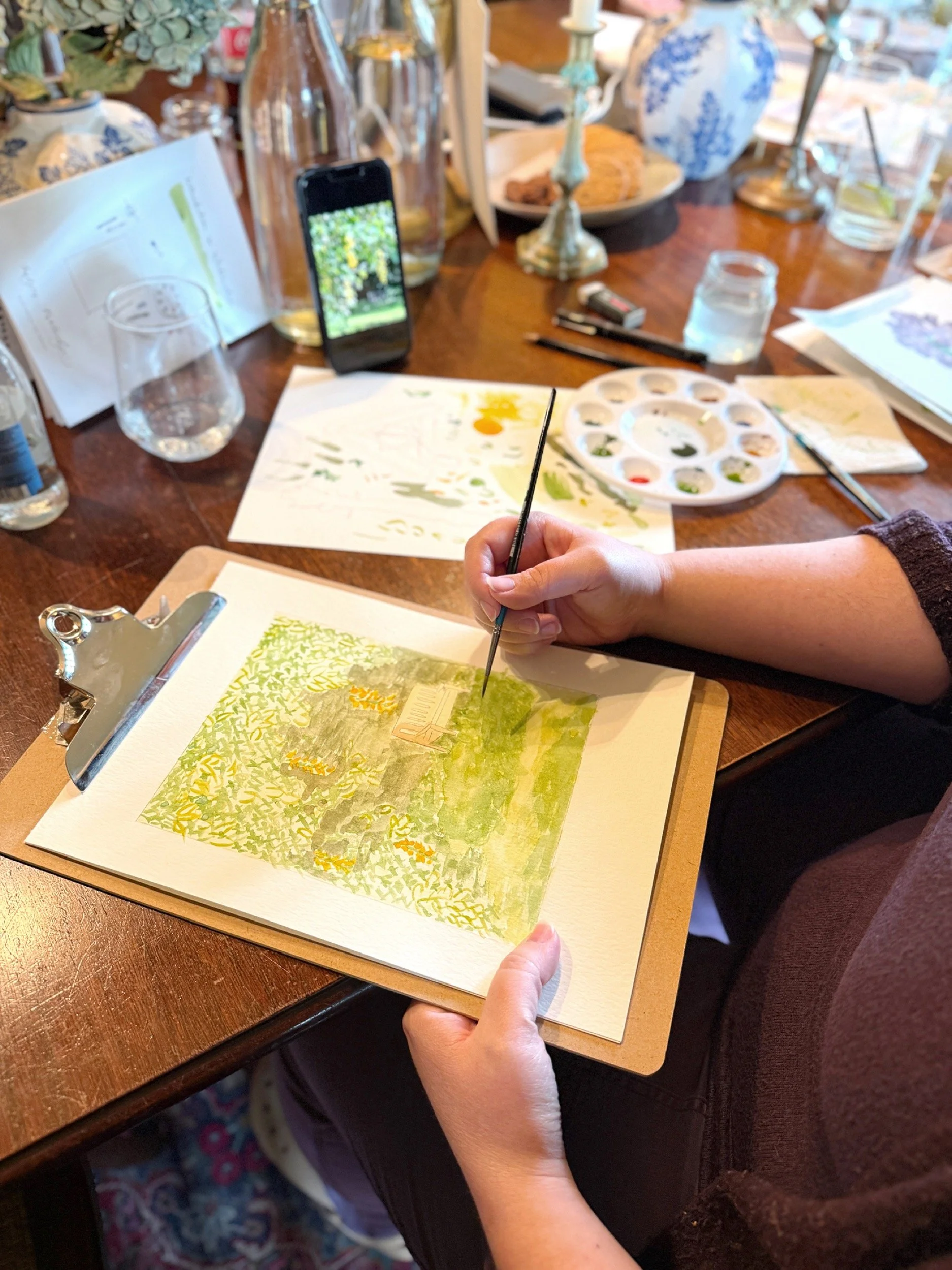 Participant painting a watercolour landscape at a corporate team day workshop indoors at Boys Hall