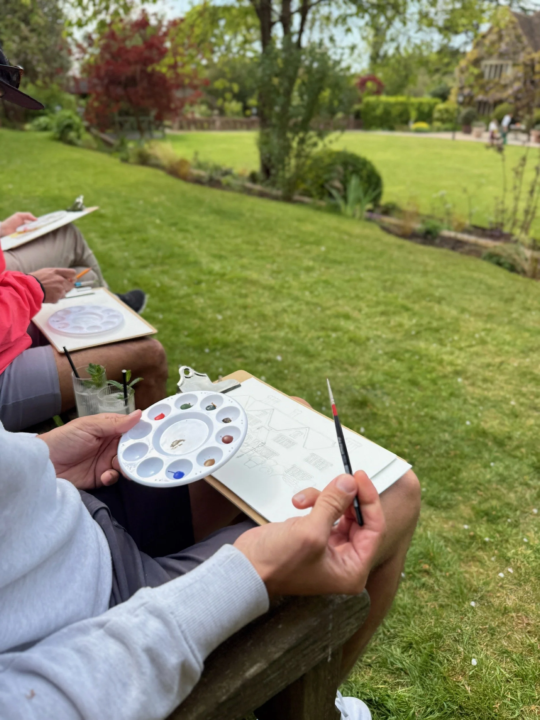 Workshop participant working outdoors on a clipboard in the gardens at Boys Hall Kent