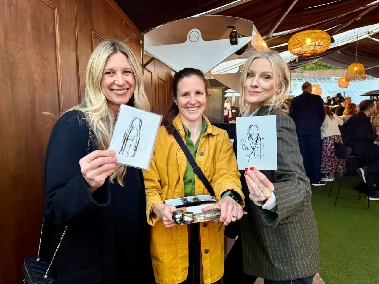 Live event illustration in action. Imogen Patridge with two guests holding up their monochrome illustrations of them at an event in London