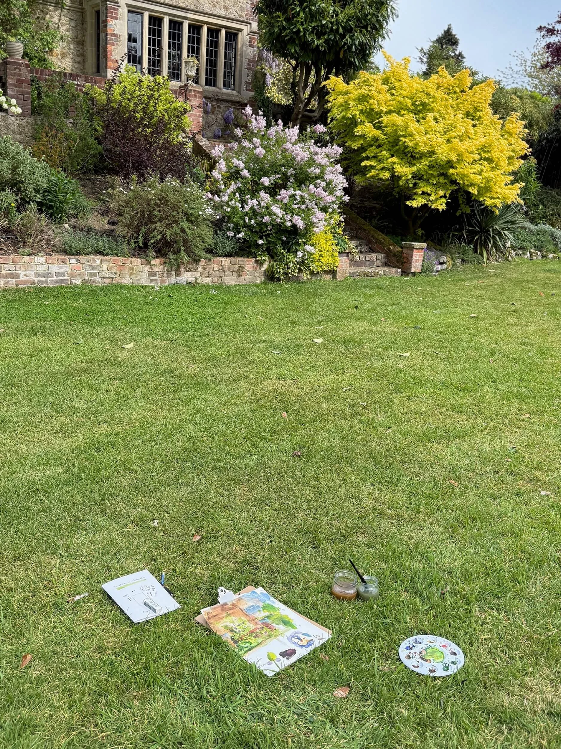 Watercolour paints and palette laid out on the grass during an outdoor painting workshop at Boys Hall in Kent