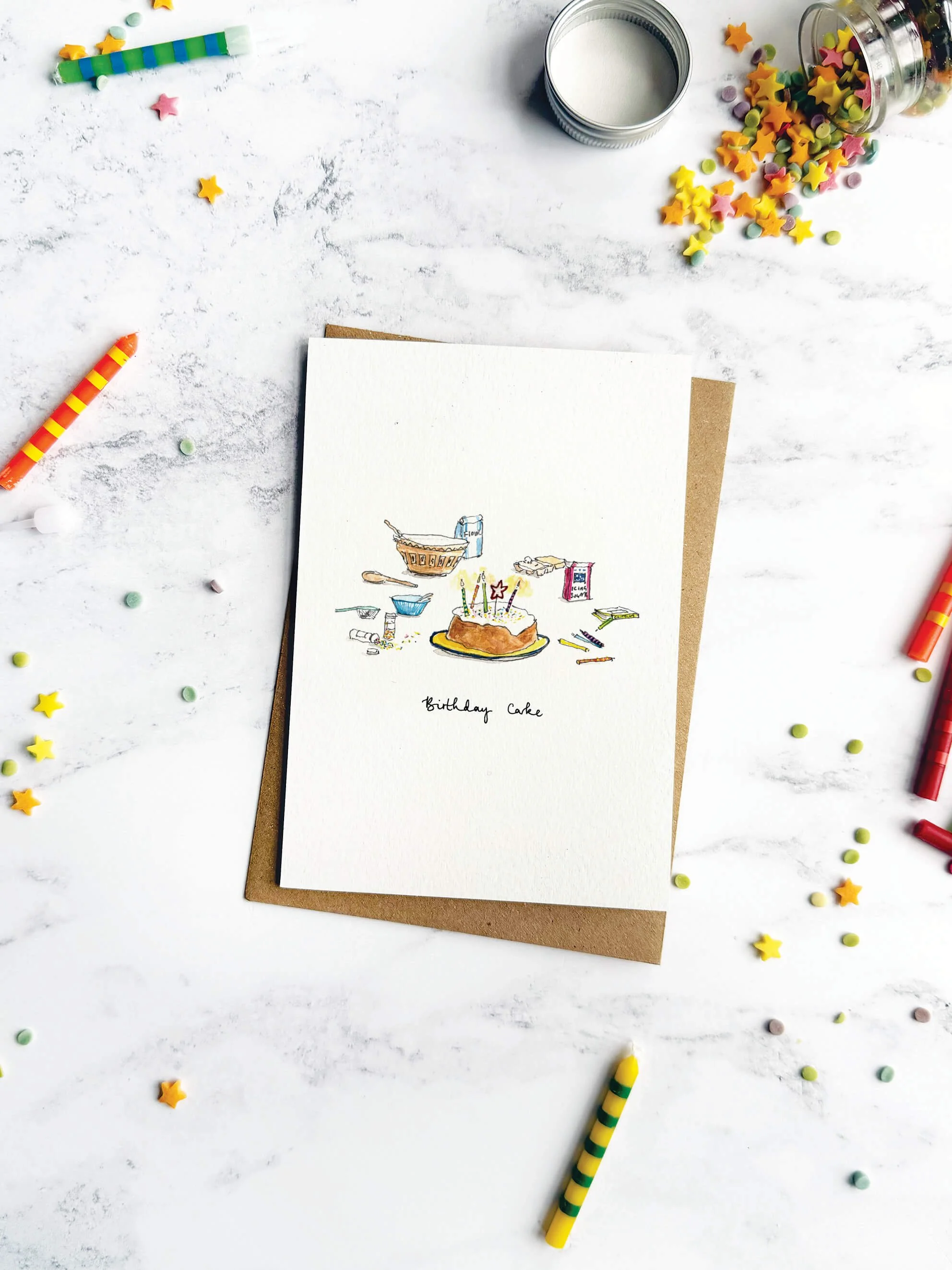 A delightful birthday card celebrating the magic of cake-making, styled with colourful  candles and scattered sprinkles on a marble backdrop.