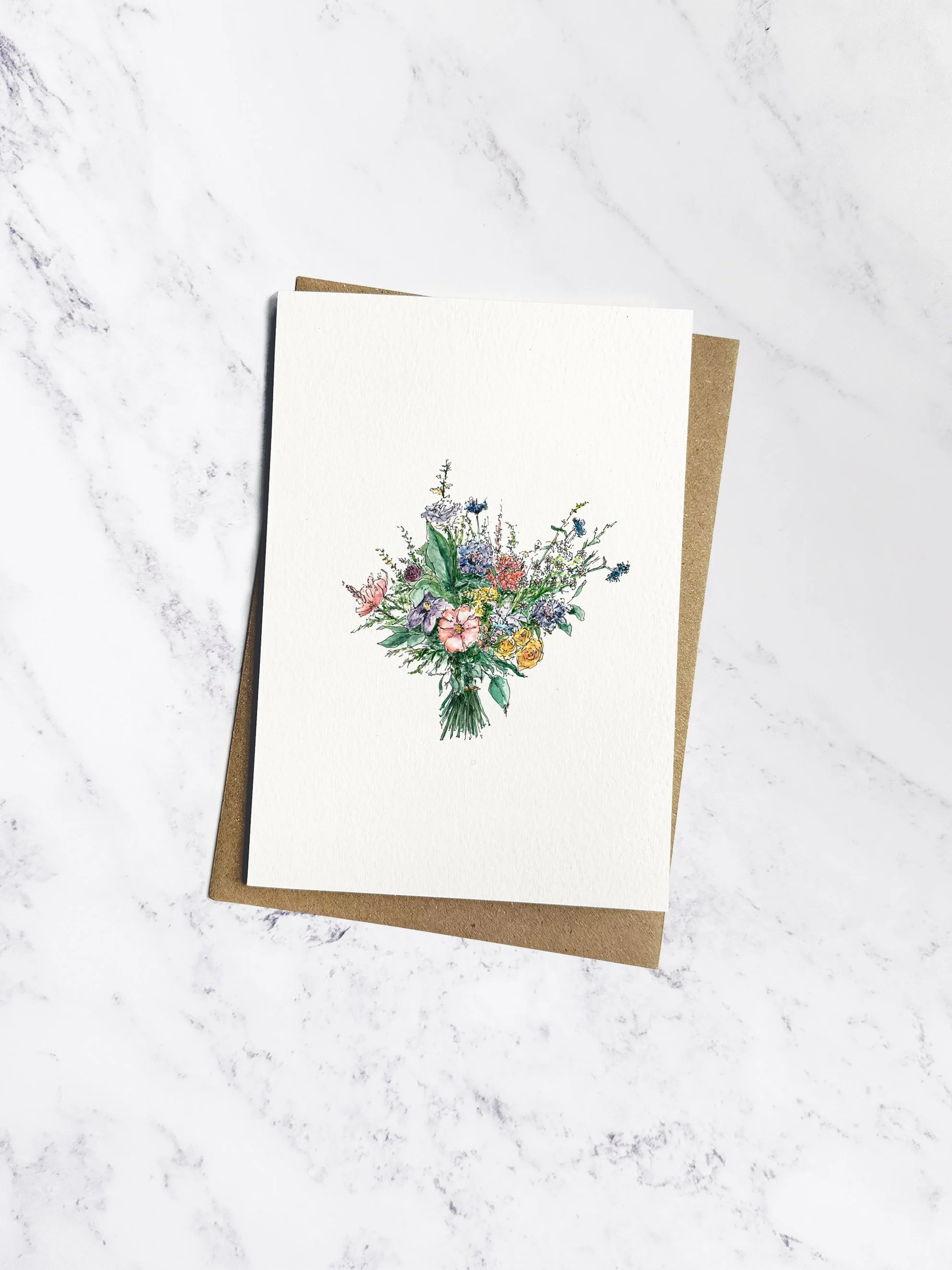 Hand painted watercolour hand tied bouquet, with beautiful British flowers including peonies & roses. The card is on a white textured paper with brown kraft envelope behind, on a marble background.