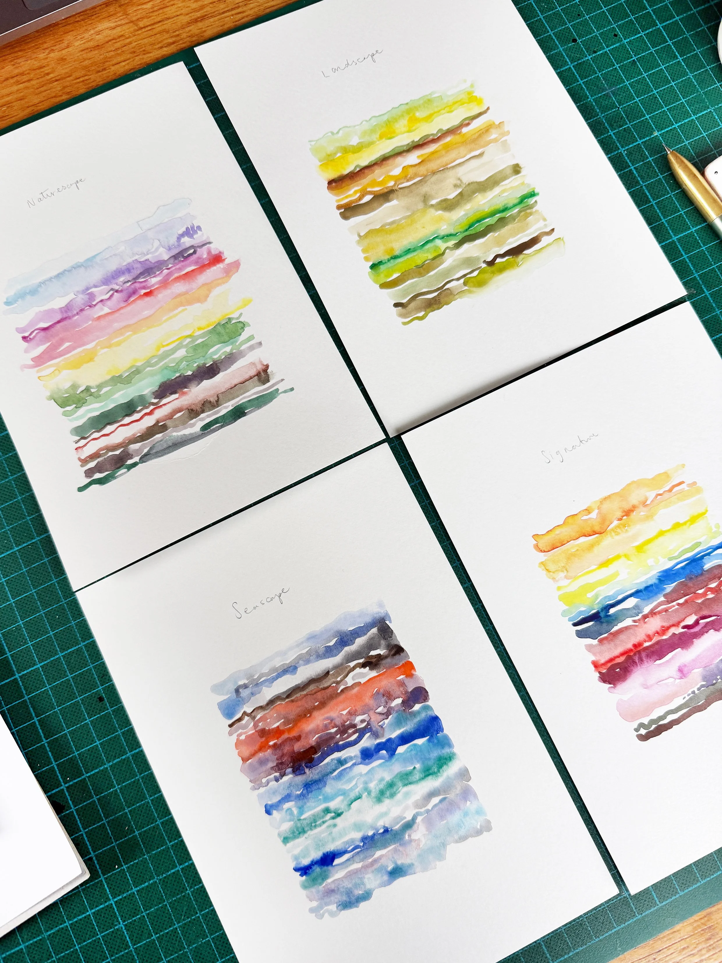 Photo of four pages of paper each with a colourful artwork in the centre, a mixture of squiggly lines of watercolour showing the range of colours that can be mixed from each Tom's Studio collection. Seascape, Landscape, Naturescape & Signature