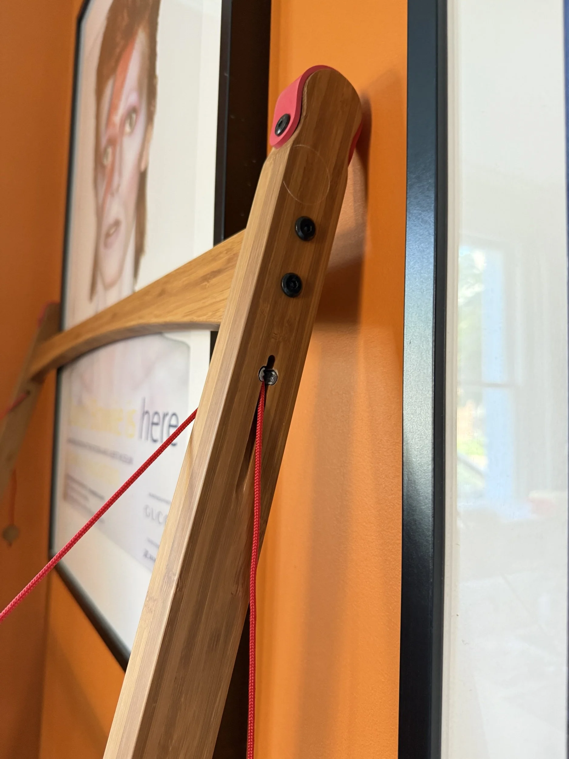 Close up of the Leandesk against the wall at the top, with a view of the small cleat fastening and strong red tension cord holding it up