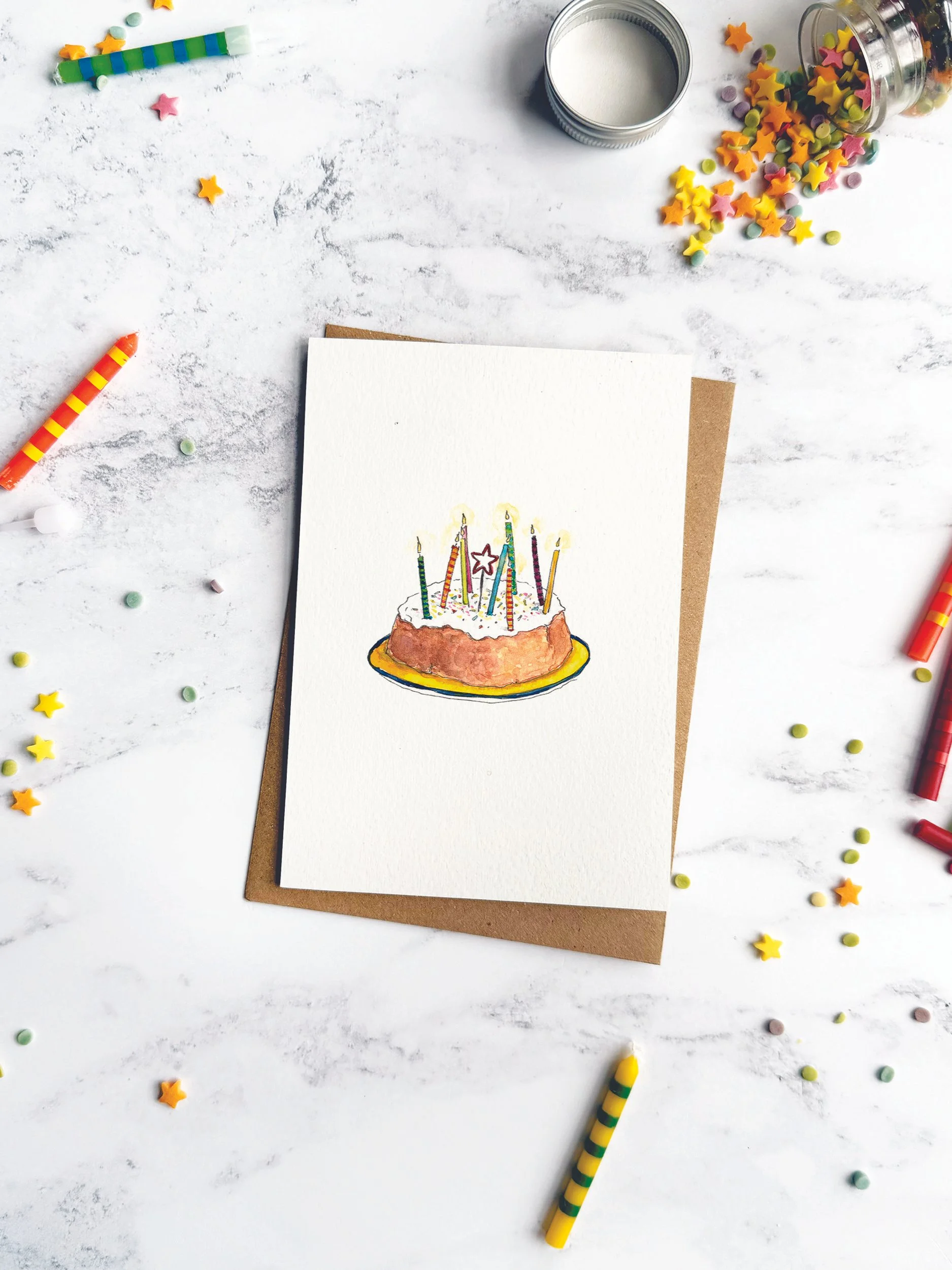 A charming birthday card celebrating the joy of homemade cakes, styled with colourful striped candles and sprinkles on a marble background.