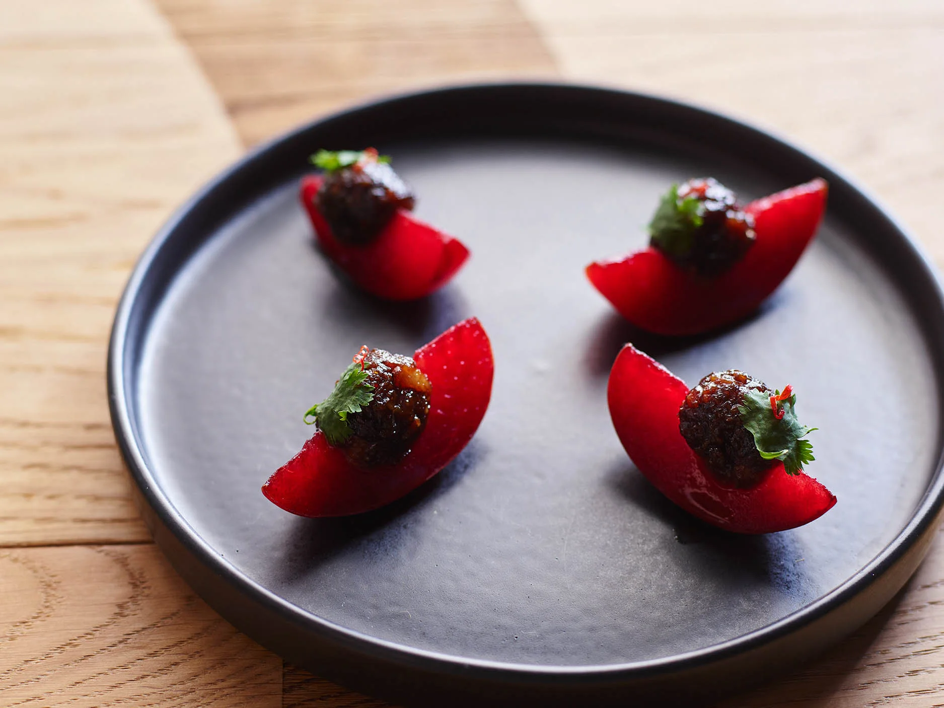 purple stone fruit on a black plate.jpg