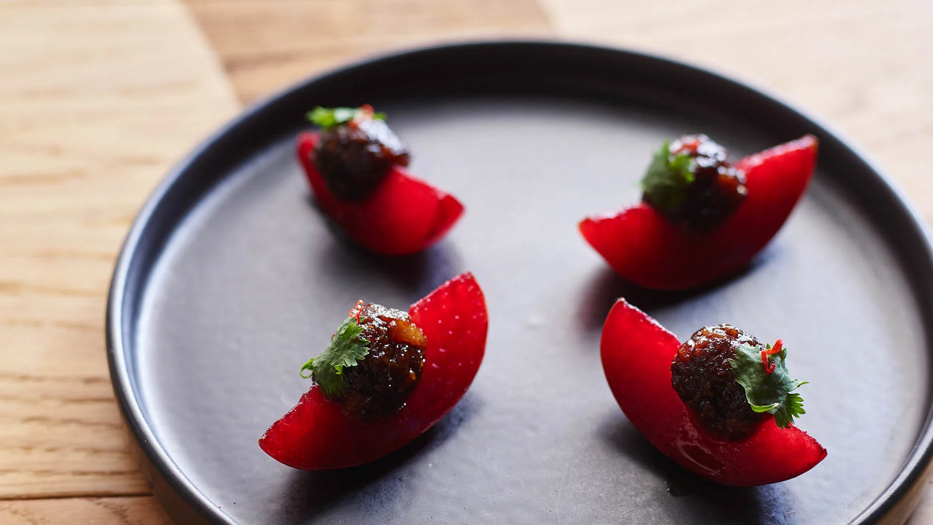 red plum wedges on a black plate.jpg