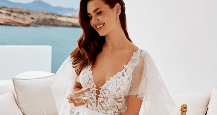 A bride in her wedding dress holding a margarita glass with body of water background