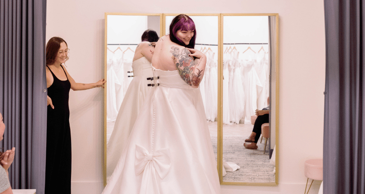 Bride trying on a wedding dress during a bridal appointment with a stylist
