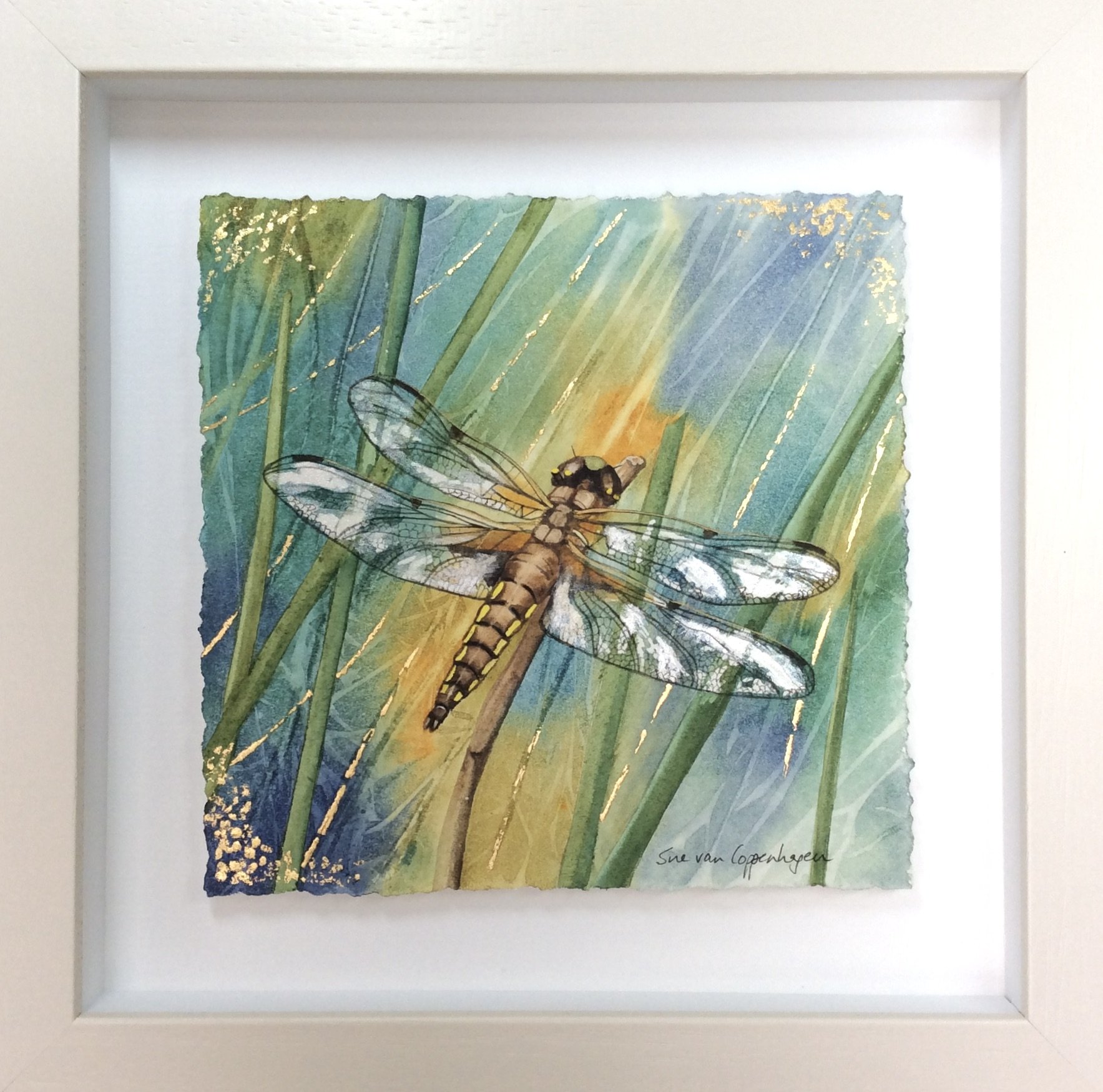 Framed painting of a shimmering dragonfly with pearly wings and streaks of gold leaf in the background