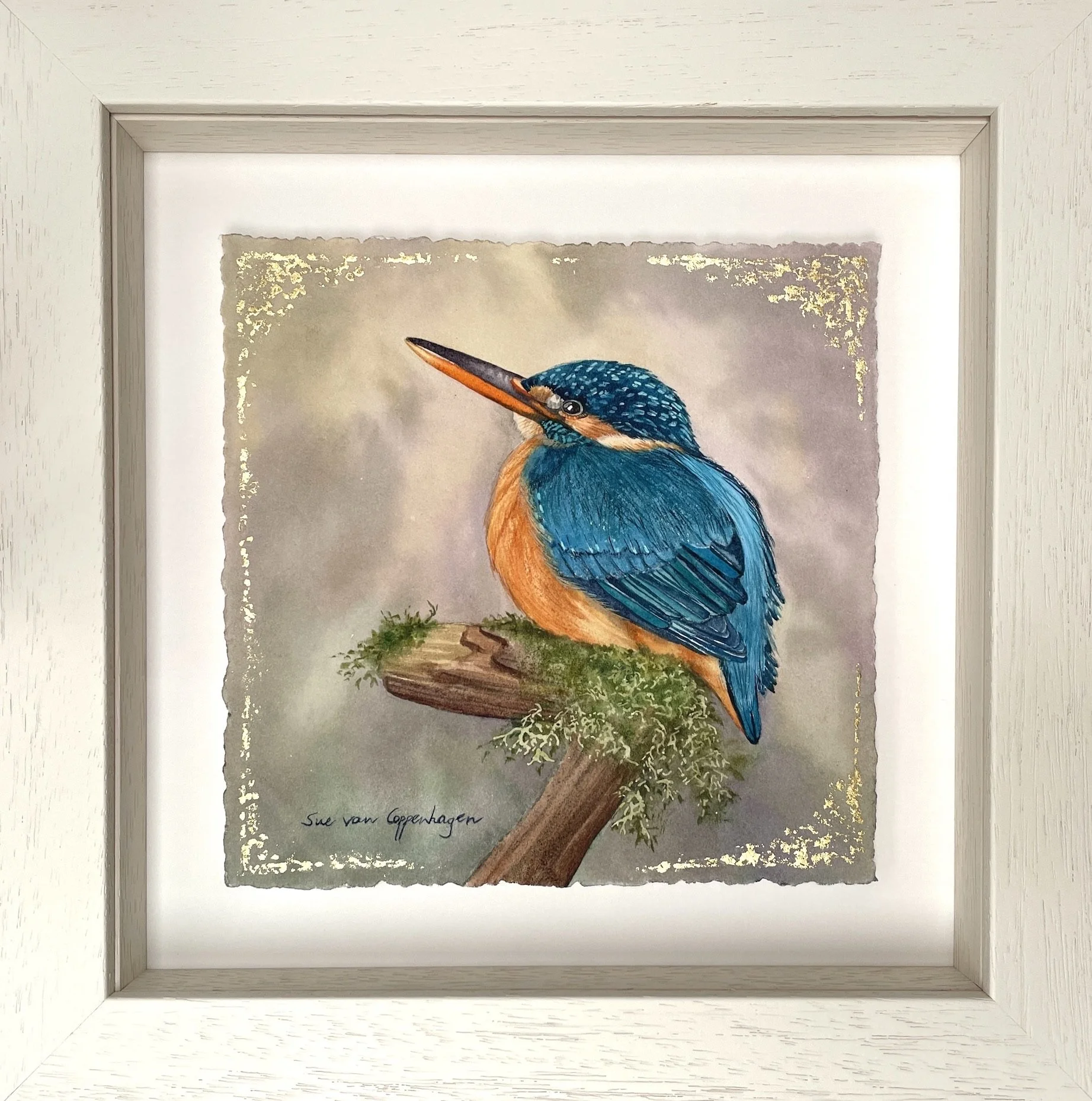 Blue kingfisher bird perched on a mossy branch, in a framed watercolour painting enhanced with touches of gold leaf