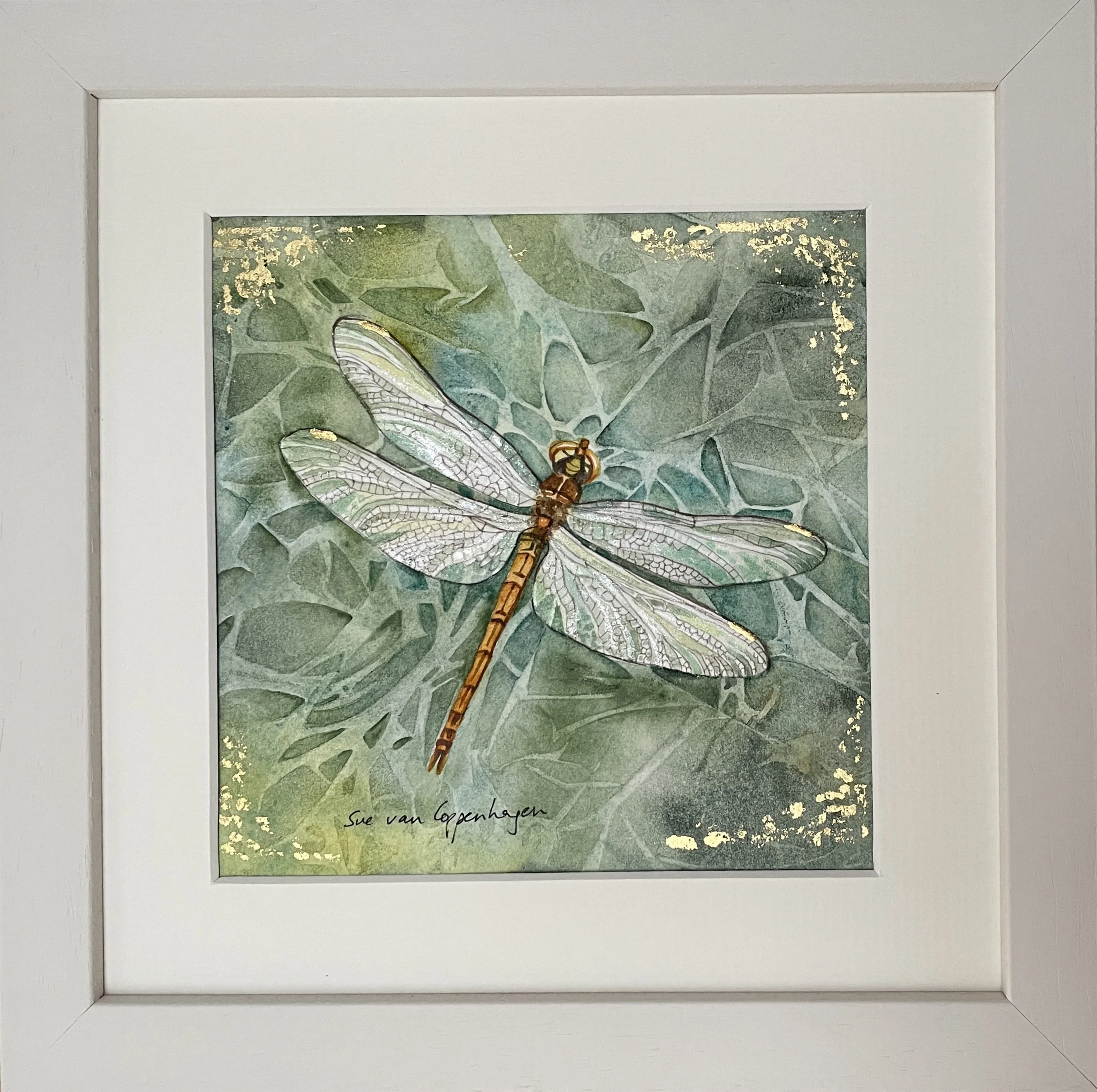 Framed painting of a shimmering dragonfly on a green patterned background