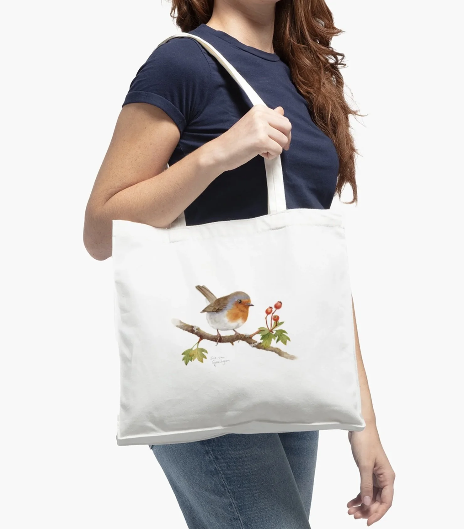 White cotton tote bag with image of a robin bird on a hawthorn branch, modelled by a woman in a blue shirt