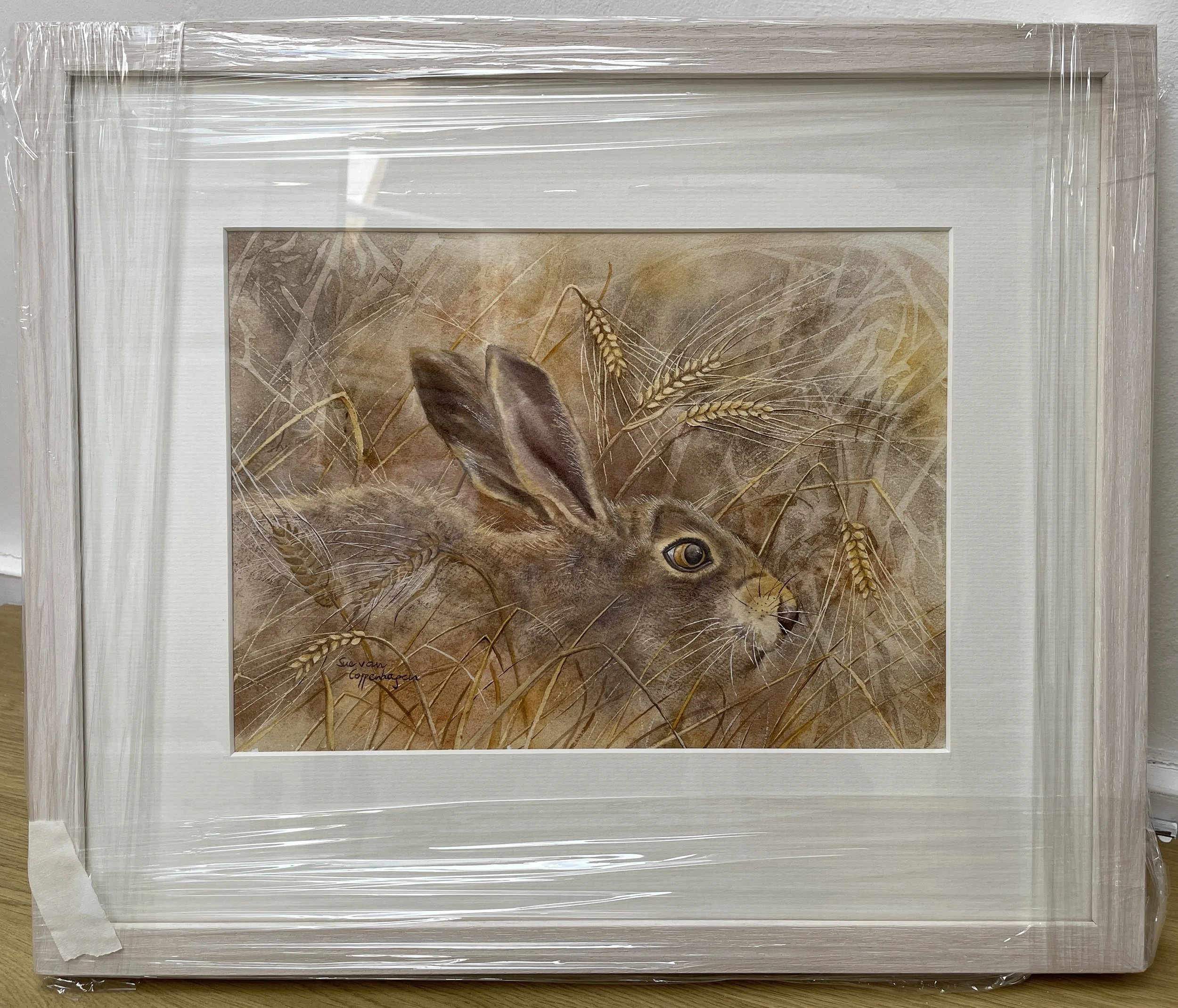 Framed painting of a hare hiding in a barley field