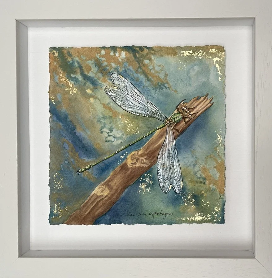 Framed painting of a green damselfly on a background of blue, green and gold