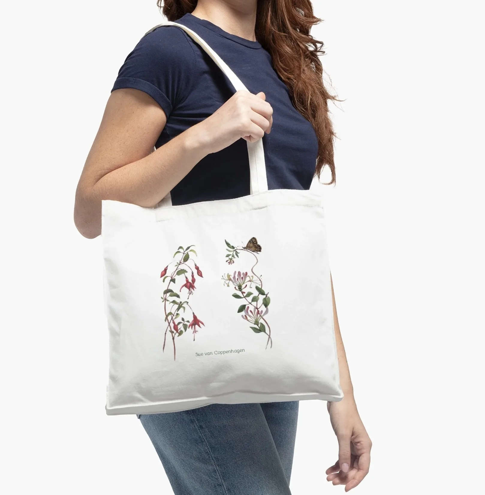 White cotton tote bag with images of fuchsia and honeysuckle, modelled by a woman wearing blue