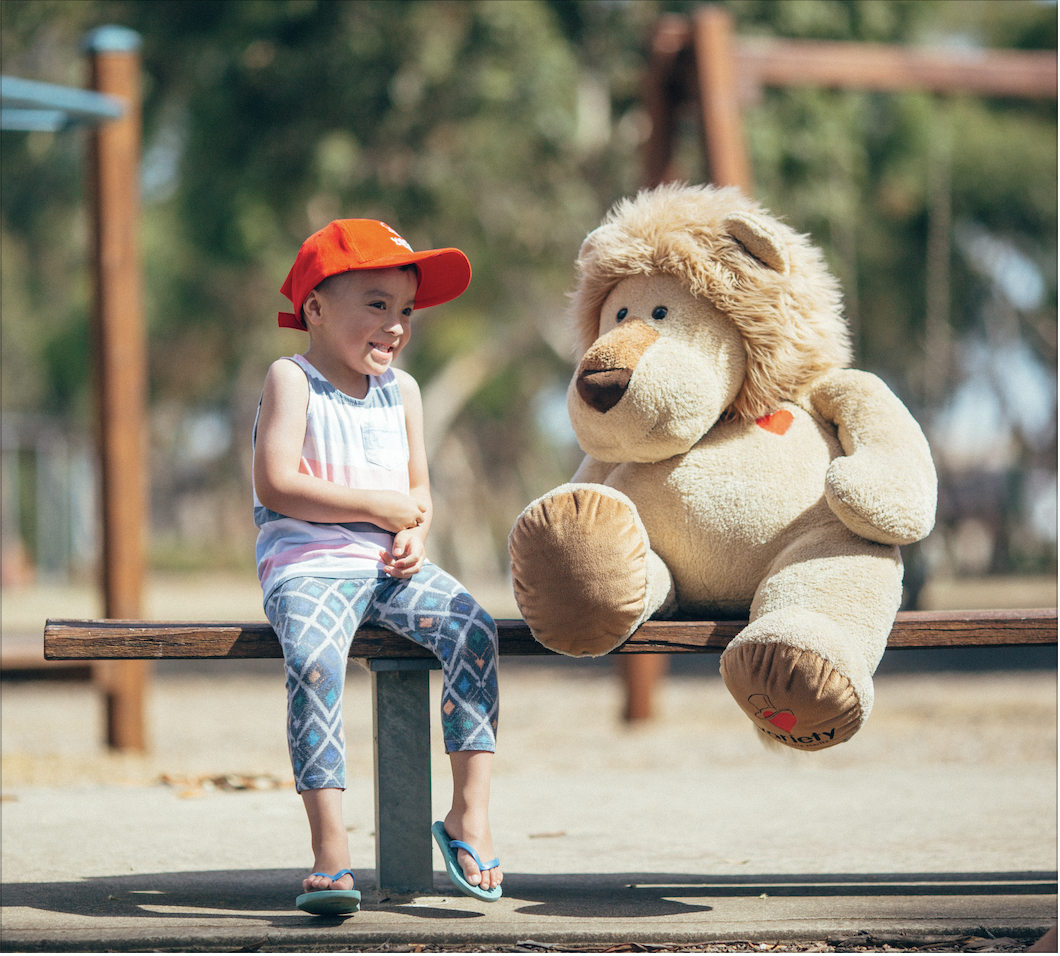 child with giant teddy bear at playground