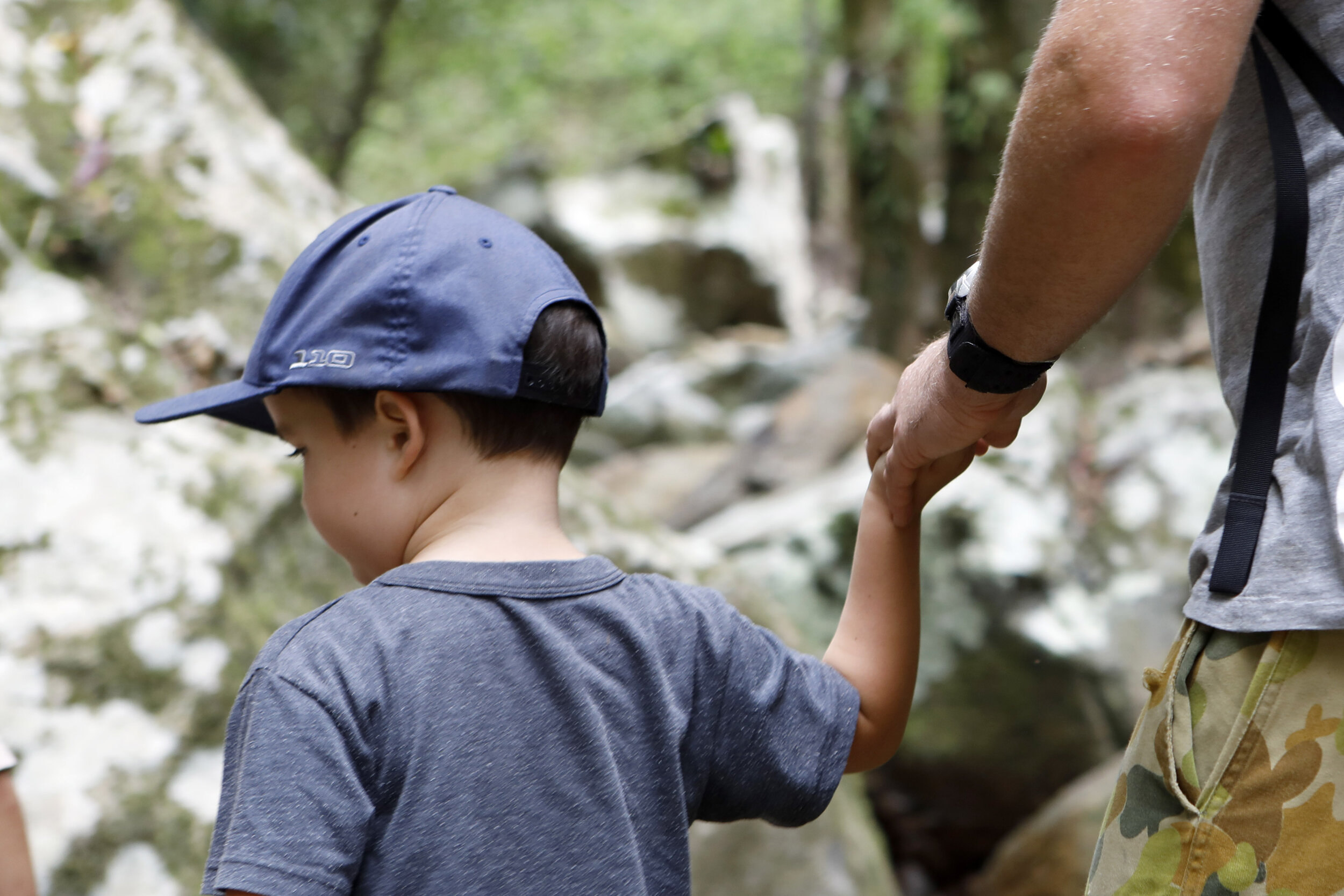 young boy holding hand of man outside