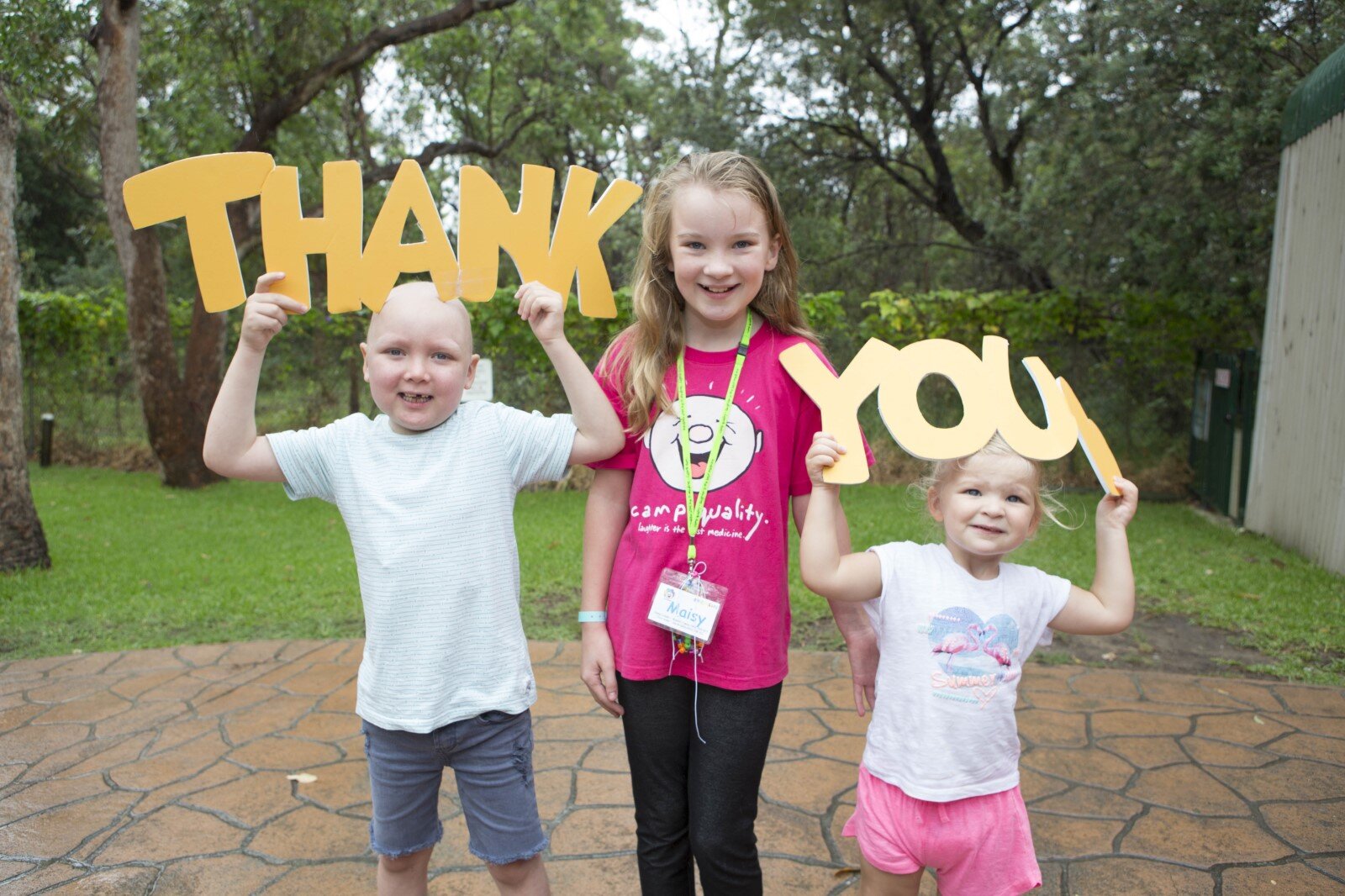 3 kids holding up thank you signs