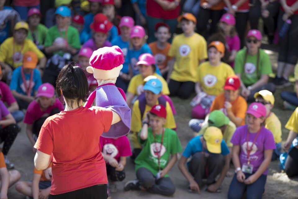 women on stage with puppets entertaining large group of people