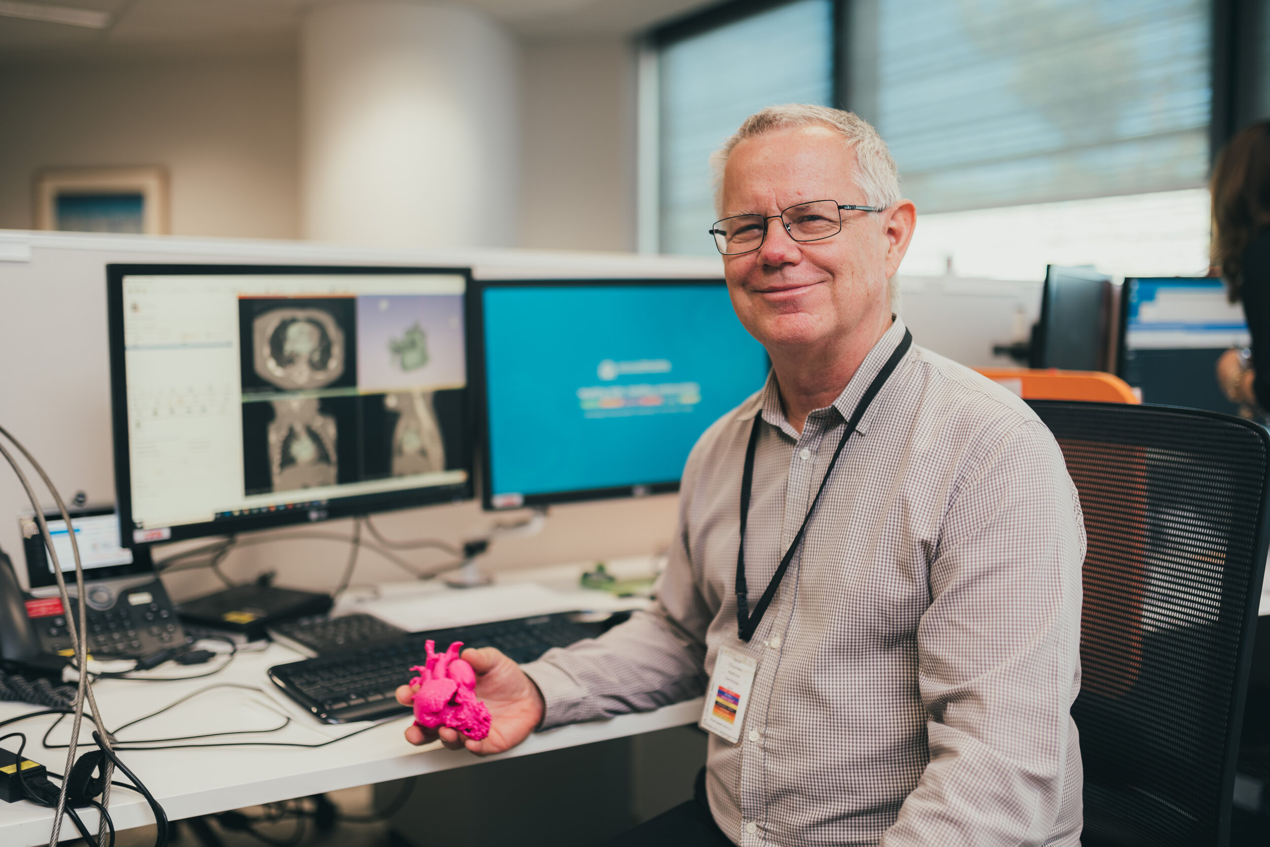 man holding 3d printed heart in front of computer