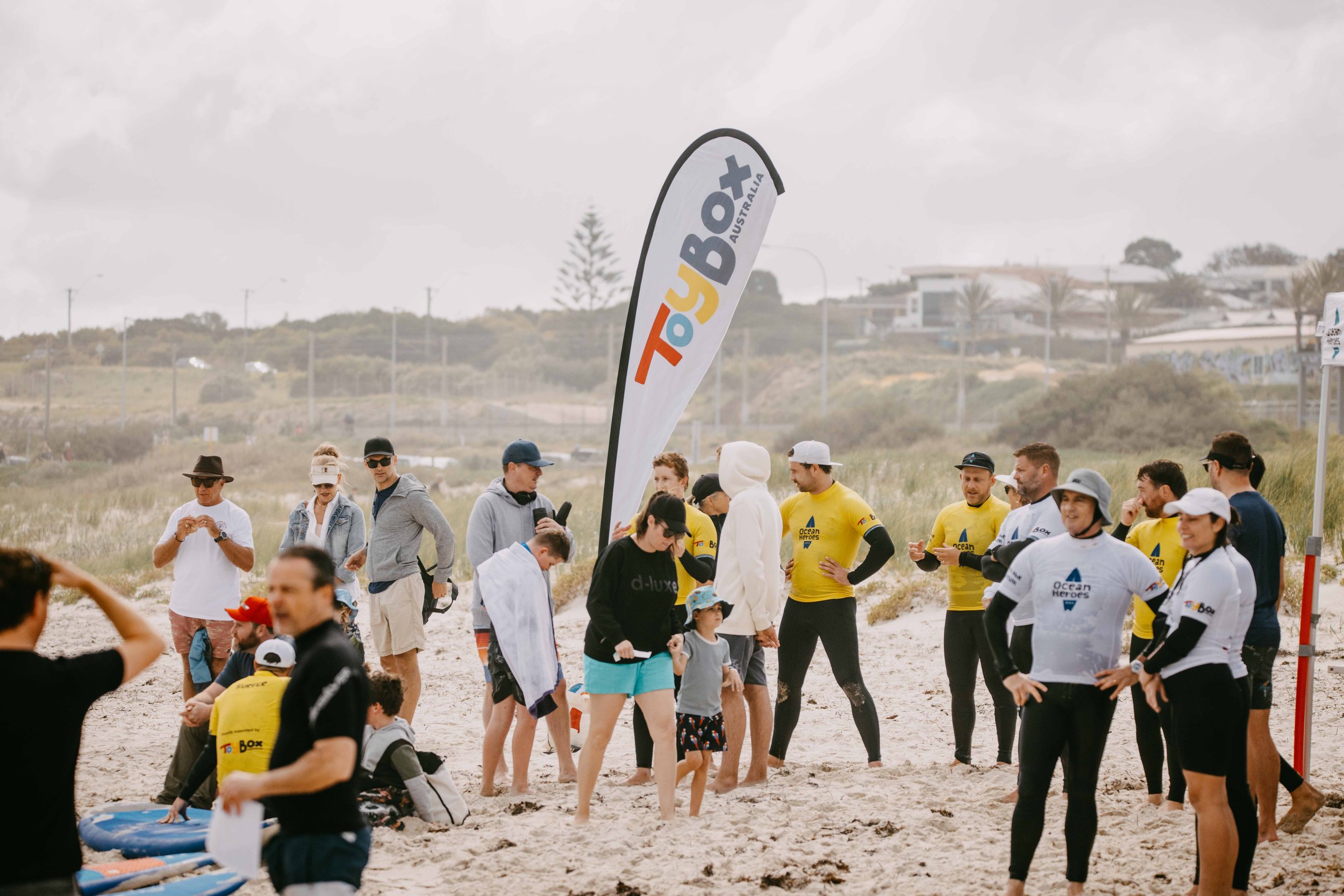 surfers and kids standing next to a flag