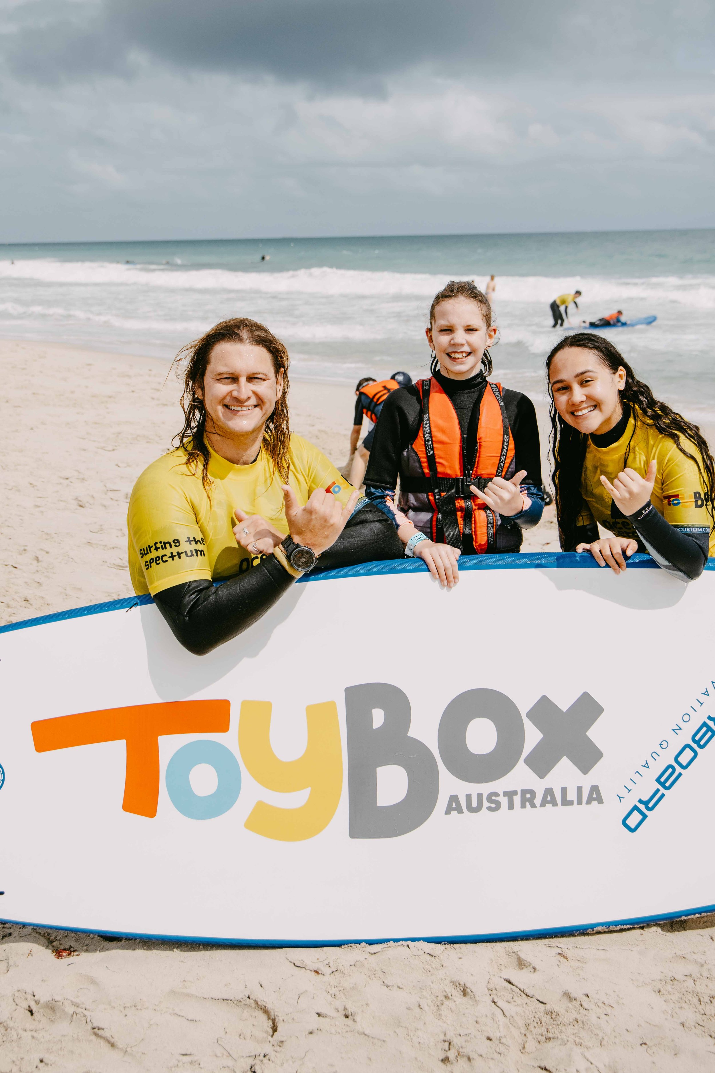 2 surfers with a young child with surfboard